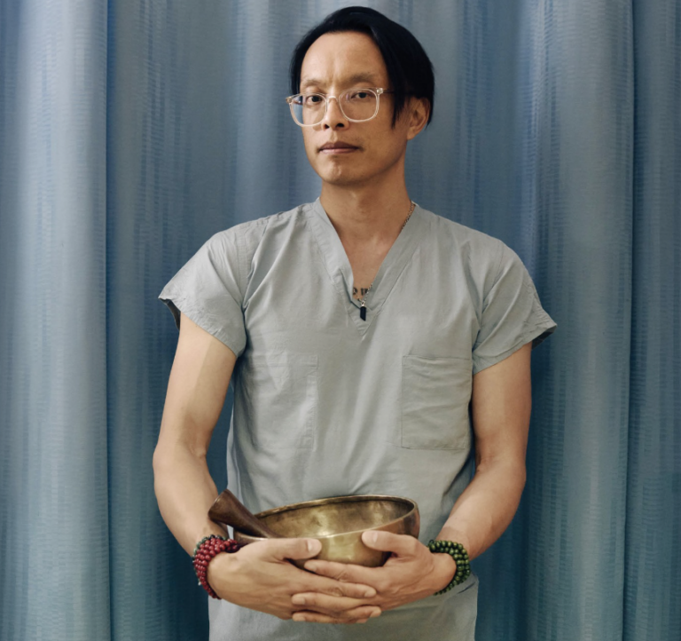 Huy Vo holding a sound bowl in his nursing uniform
